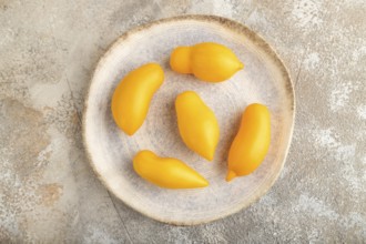 Yellow tomatoes on plate on brown concrete background. Top view, flat lay, close up. healthy food,