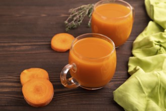 Two glasses with carrot juice, on wooden background and green textile. Diet, healthy eating concept