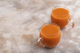Two glasses with carrot juice, on brown concrete background. Diet, healthy eating concept. side