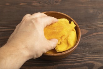 Dried Mango in wooden bowl with hand on brown wooden background. Side view, close up. healthy food,