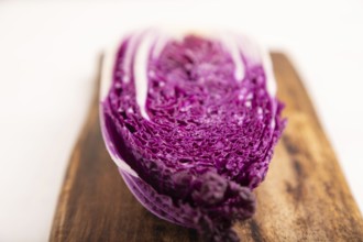 Purple Chinese cabbage on cutting board on white wooden background, top view, flat lay, close up,