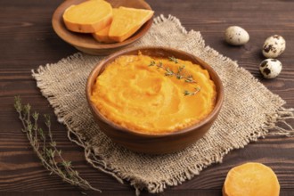 Sweet potato porridge in wooden bowl on wooden background and linen textile. Diet, healthy eating