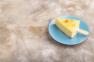 Yellow Cake pop with sprinkles on blue ceramic plate on brown concrete background, side view, copy
