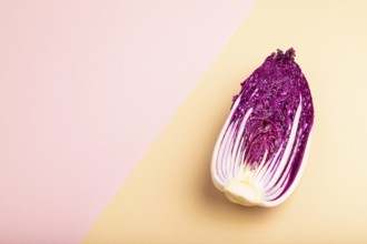 Purple Chinese cabbage on pink and orange pastel paper background, side view, copy space,