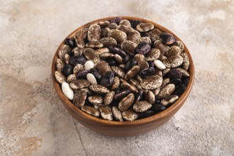 Wooden bowl with Kidney beans on brown concrete background, side view, close up, minimalism