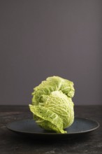 Green lettuce on blue plate on black concrete background. Side view, copy space. healthy food,
