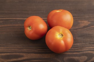 Red tomato on brown wooden background. Side view, close up. healthy food, vegetable, minimalism