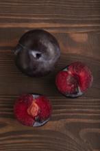 Purple Plum Cut in half on brown wooden background. Top view, flat lay, close up. healthy food,