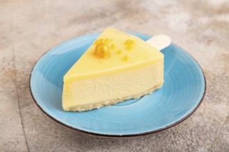 Yellow Cake pop with sprinkles on blue ceramic plate on brown concrete background, side view, close