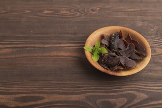 Armenian Basturma dried meat on wooden bowl with pepper and herbs on brown wooden background. Side