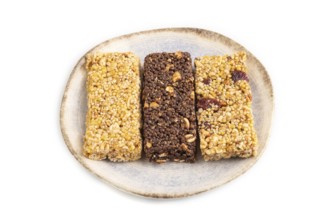Granola bars with caramel, nuts, flakes in ceramic plate isolated on white background. Side view,