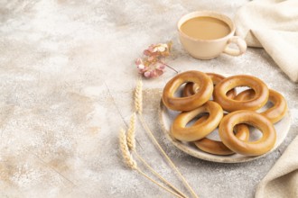 Homemade Ring Bagel with cup of coffee on brown concrete background and linen textile. side view,