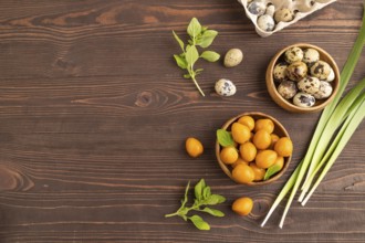 Pile of Smoked Quail eggs in bowl on a brown wooden background. top view, flat lay, copy space