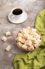 Orange and pink marshmallow in ceramic bowl on brown concrete background and green textile, side