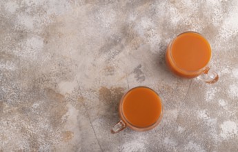 Two glasses with carrot juice, on brown concrete background. Diet, healthy eating concept. top