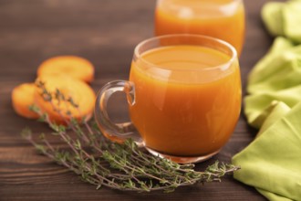 Two glasses with carrot juice, on wooden background and green textile. Diet, healthy eating concept