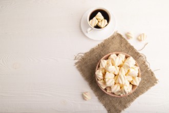 Orange and pink marshmallow in ceramic bowl on white wooden background and linen textile, top view,