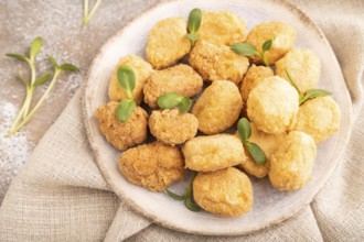 Fried crispy Chicken Nuggets with ketchup, microgreen on brown concrete background and linen