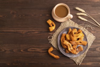 Crunchy biscuit Brushwood cookies sprinkled with powdered sugar on brown wooden background and