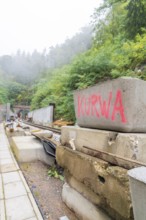 Baustelle mit Betonblöcken, auf einem steht rotes Graffiti 'Kurwa', Bau der Hermann Hessenahn,