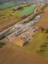 Luftaufnahme einer weitläufigen Landschaft mit Bauplatz und umgebenden Feldern und Straßen, Bau der