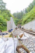 Bauarbeiten an einer Bahnstrecke mitten im Wald mit Betonmauern und Schienen, Bau der Hermann