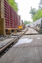 Baustelle entlang einer Schienenstrecke mit Holzarbeiten und Arbeitern, Bau der Hermann Hessenahn,