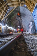 Tunnelbau mit Schienen, Maschinen, beleuchteter Atmosphäre und einem Bauarbeiter in Aktion, Bau der