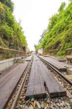 Eisenbahnschienen mit Holzplanken in einer eingefassten, grünen Bauumgebung, Bau der Hermann