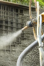 Betonspritzmaschine bei der Anwendung von Spritzbeton auf Gitterstruktur, Bau der Hermann