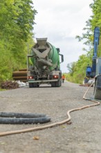 Zementlaster auf einer Baustellenstraße, umgeben von grüner Vegetation, Bau der Hermann Hessenahn,