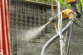 Detailansicht einer Maschine, die Beton entlang eines Stahlgitters sprüht, Bau der Hermann