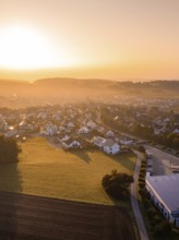 Dorfansicht bei Sonnenaufgang mit beleuchteten Dächern und umliegenden Feldern, Gechingen,