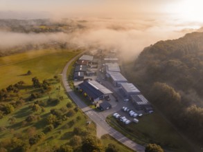 Luftaufnahme eines Industriegebiets bei nebligem Morgenlicht mit umliegenden Feldern, Gechingen,