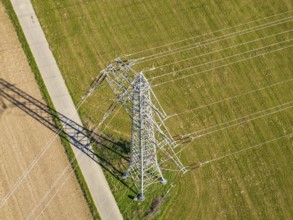 Hochspannungsmast steht auf einer Wiese, Schatten fällt über Felder im Sonnenlicht, Nagold,