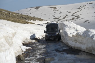 Van navigiert durch schmale, schneebedeckte Bergstraße bei Sonnenlicht, mit dem Camper zum Aragaz,