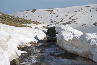 Van fährt auf schneebedeckter Bergstraße unter klarem Himmel, mit dem Camper zum Aragaz, Aragats,