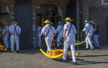 Männer in weißer Kleidung transportieren Käse auf einem Markt zur ehemaligen Stadtwaage,