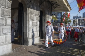 Männer mit Käse laufen durch ein historisches Marktgelände mit Publikum, ehemalige Stadtwaage,