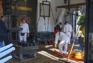 Männer mit roten Hüten bereiten Käse auf einem traditionellen Markt vor, ehemalige Stadtwaage, Käse