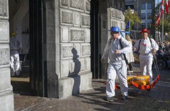 Männer mit blauen und roten Hüten bringen Käse auf den Markt zur ehemaligen Stadtwaage, Käseträger,