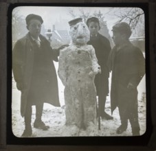 Magic lantern slide three boys making a snowman in a garden, England, UK c 1900-1910