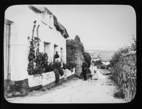 Magic lantern slide c 1900-1910 of people in country lane of village with thatched cottages
