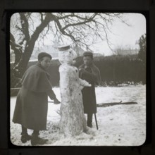 Magic lantern slide two boys making a snowman in a garden, England, UK c 1900-1910