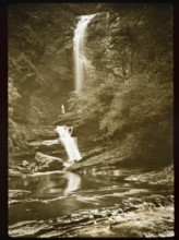 Magic lantern slide c 1900-1910 woman standing in distance beneath waterfall in rocky river gorge