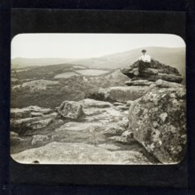 Magic lantern slide of woman sitting on mountain peak in countryside England, UK circa 1900