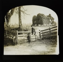 Magic lantern slide of children by gate entrance with mysterious looking ivy covered house standing