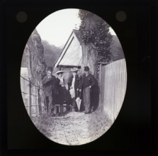 Magic lantern slide two well dressed couples one older one younger standing in alleyway in rural