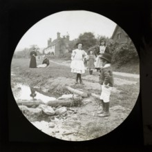 Magic lantern slide of mothers with children outside playing by a stream in a village rural