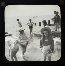 Magic lantern slide of children boys and girls paddling playing in the sea, UK circa 1900
